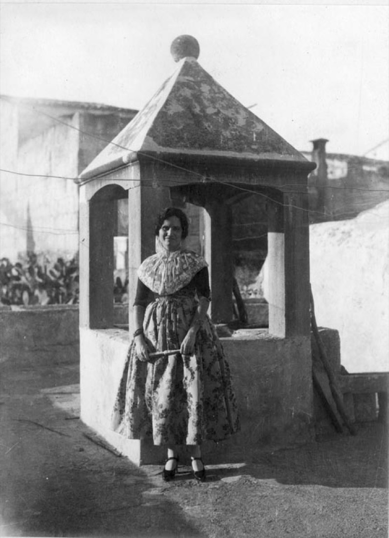 Noia amb vestit de mudar tradicional davant d'un pou